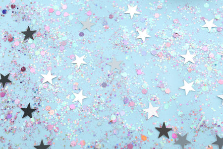 Shiny glitter on light blue background, flat lay