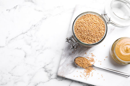 Flat lay composition with mustard seeds on white marble table, space for textの写真素材