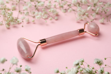 Natural face roller and flowers on pink backgroundの写真素材
