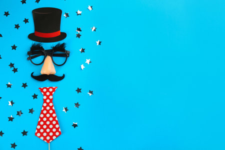 Flat lay composition with clown's face made of party glasses, cylinder and tie on light blue background. Space for textの写真素材