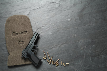 Balaclava, pistol and bullets on black table, flat lay. Space for textの写真素材