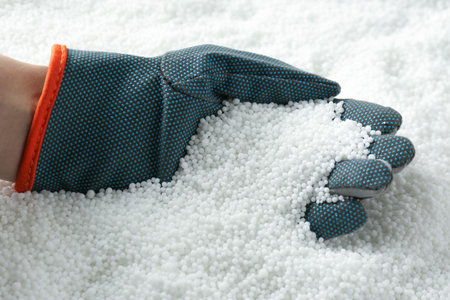 Farmer taking pellets of ammonium nitrate from pile, closeup. mineral fertilizer