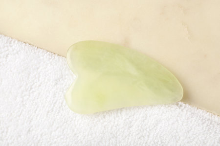 Jade gua sha tool and board on white towel, closeupの写真素材