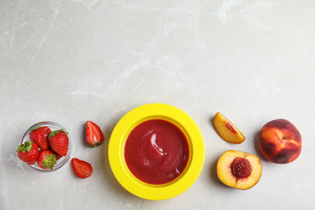 Baby food in bowl and fresh ingredients on light gray table, flat lay. Space for textの写真素材