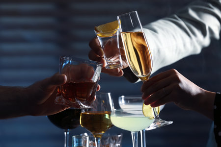 People with different alcohol drinks clinking glasses indoors, closeupの写真素材