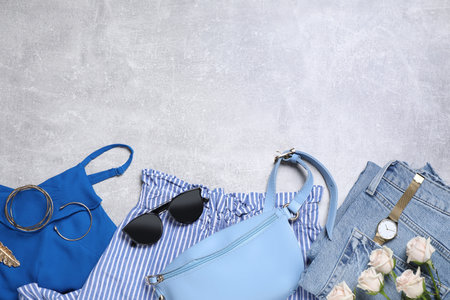 Stylish women's outfit and flowers on light gray table, flat lay. Space for textの写真素材