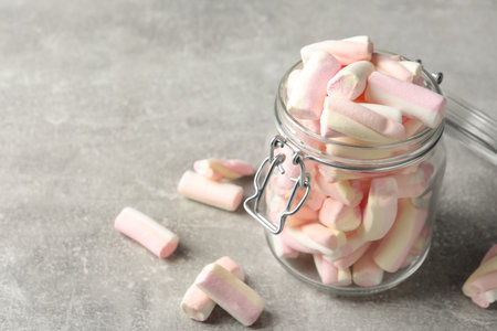 Glass jar with tasty marshmallows on light gray table, closeup. Space for textの写真素材