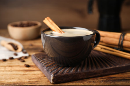 Cup of hot coffee with aromatic cinnamon on wooden tableの写真素材