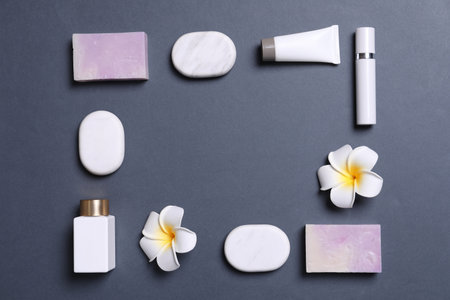 Frame of cosmetic products, spa stones and flowers on gray background. Space for textの写真素材