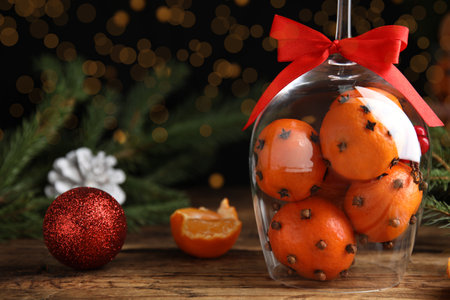 Christmas composition with tangerine pomander balls in wineglass on wooden table. Space for textの写真素材