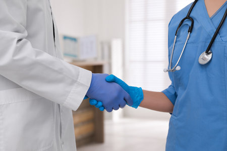 Doctors in medical gloves giving handshake at hospital, closeupの写真素材