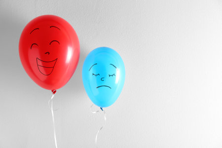 Air balloons with drawn sad and happy faces on white background. Space for textの写真素材