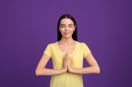 Young woman meditating on purple background. stress relief exerciseの写真素材