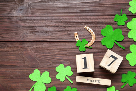 Flat lay composition with clover leaves and block calendar on wooden table, space for text. St....