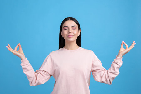 Young woman meditating on light blue background. stress relief exerciseの写真素材