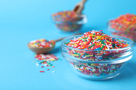 Colorful sprinkles in bowl on light blue background, closeup with space for text. Confectionery decorの写真素材
