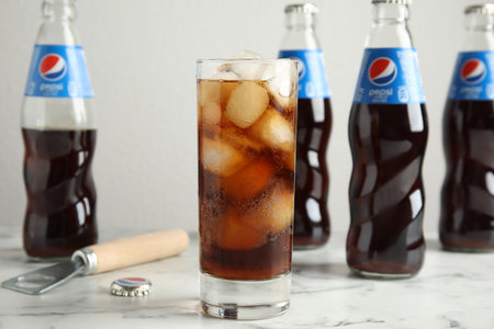 MYKOLAIV, UKRAINE - FEBRUARY 10, 2021: Glass and bottles of Pepsi on white marble tableのeditorial素材