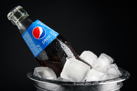 MYKOLAIV, UKRAINE - FEBRUARY 11, 2021: Glass bottle of Pepsi and ice cubes in bucket on black background, closeupのeditorial素材