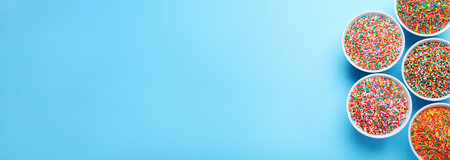 Colorful sprinkles in bowls on light blue background, flat lay with space for text. Confectionery decorの写真素材