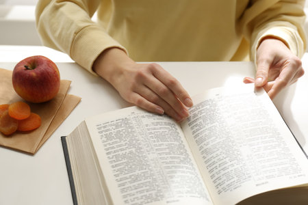 Woman with Holy Bible at white table indoors, closeup. Great Lent seasonの写真素材