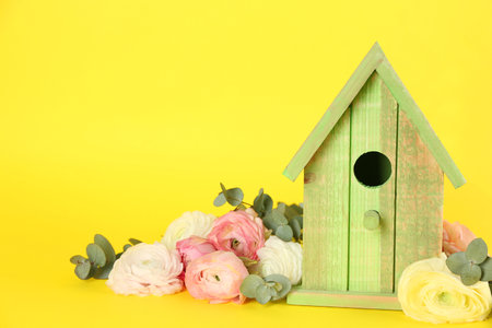 Stylish bird house and fresh eustoma on yellow background. Space for textの写真素材