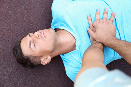Passerby performing CPR on unconscious man outdoors, top view. First aidの写真素材