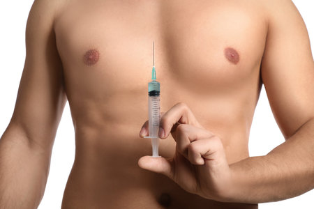 Athletic man with syringe on white background, closeup. Doping conceptの写真素材