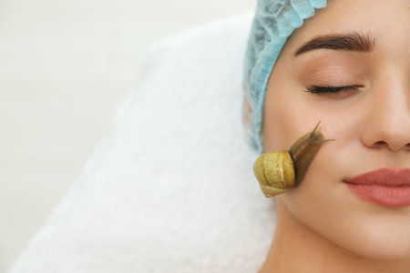 Young woman receiving snail facial massage in spa salon. Space for textの写真素材