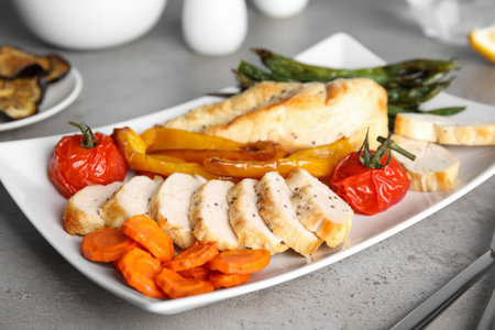 Tasty cooked chicken fillet and vegetables served on gray table. Healthy meals from air fryerの写真素材