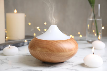 Aroma oil diffuser and burning candles on white marble tableの写真素材