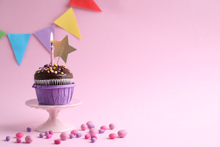 Delicious chocolate dessert with burning candle and candies on pink background. Space for textの写真素材