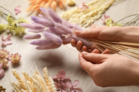 Florist making bouquet of dried flowers on white wooden table, closeupの写真素材
