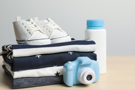 Baby clothes, shoes and toy camera on wooden table, closeupの写真素材