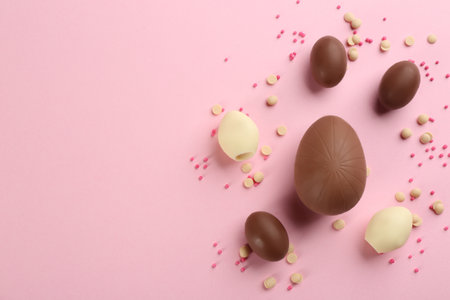 Sweet chocolate eggs on pink background, flat lay. Space for textの写真素材