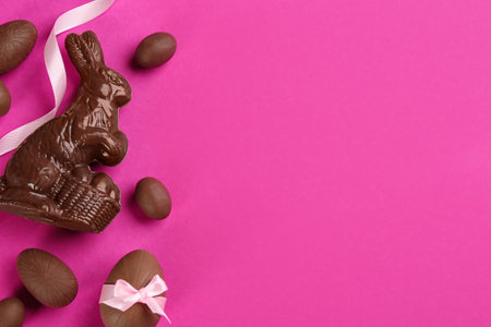 Flat lay composition with chocolate Easter bunny and eggs on pink background. Space for textの写真素材