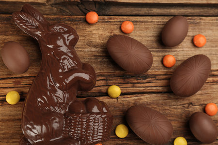 Chocolate Easter bunny, candies and eggs on wooden table, flat layの写真素材