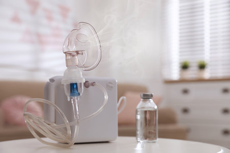 Modern nebulizer with face mask on white table indoors. Inhalation equipmentの写真素材