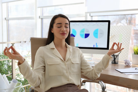 Businesswoman meditating at workplace in office. stress relief exerciseの写真素材