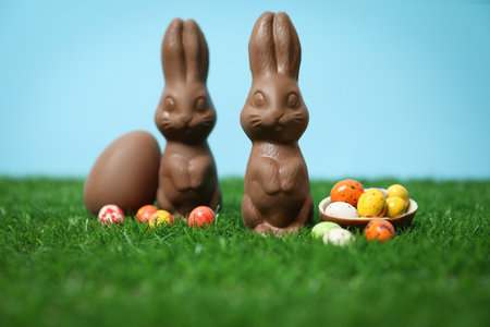Chocolate Easter bunnies and eggs on green grassの写真素材