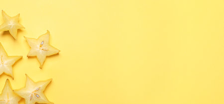Delicious carambola slices on yellow background, flat lay. Space for textの写真素材
