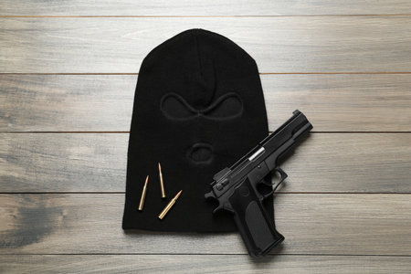 Balaclava, pistol and bullets on wooden table, flat layの写真素材
