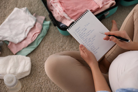 Pregnant woman writing packing list for maternity hospital at home, above viewの写真素材