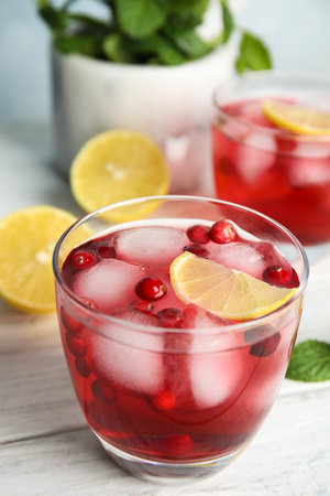 Tasty refreshing cranberry cocktail with lemon on white wooden table, closeupの写真素材