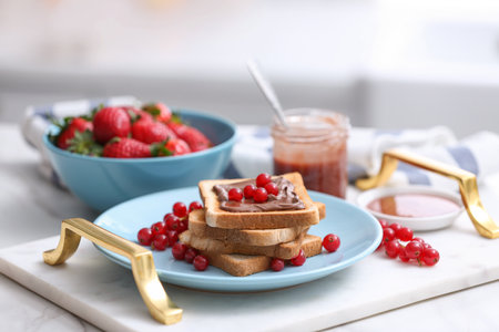 Toasted bread with chocolate spread and fresh cranberries on tray in kitchenの写真素材