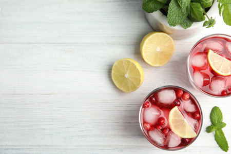 Tasty refreshing cranberry cocktails with lemon on white wooden table, flat lay. Space for textの写真素材