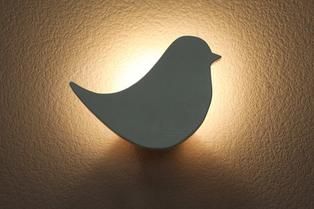 Bird shaped glowing night lamp on wallの写真素材
