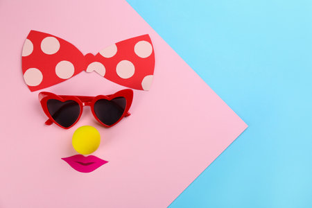 Flat lay composition with clown's face made of sunglasses and bow on color background. Space for textの写真素材