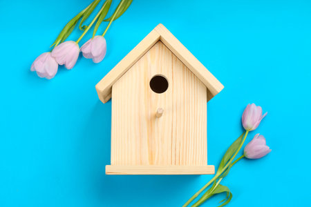 Beautiful bird house and pink tulips on light blue background, flat layの写真素材