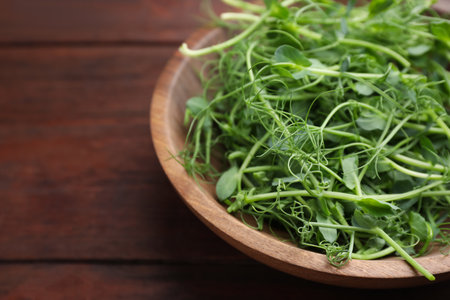 Plate with fresh microgreens on brown wooden table, closeupの写真素材