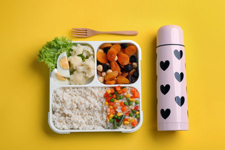 Thermo and lunch box with food on yellow background, flat layの写真素材